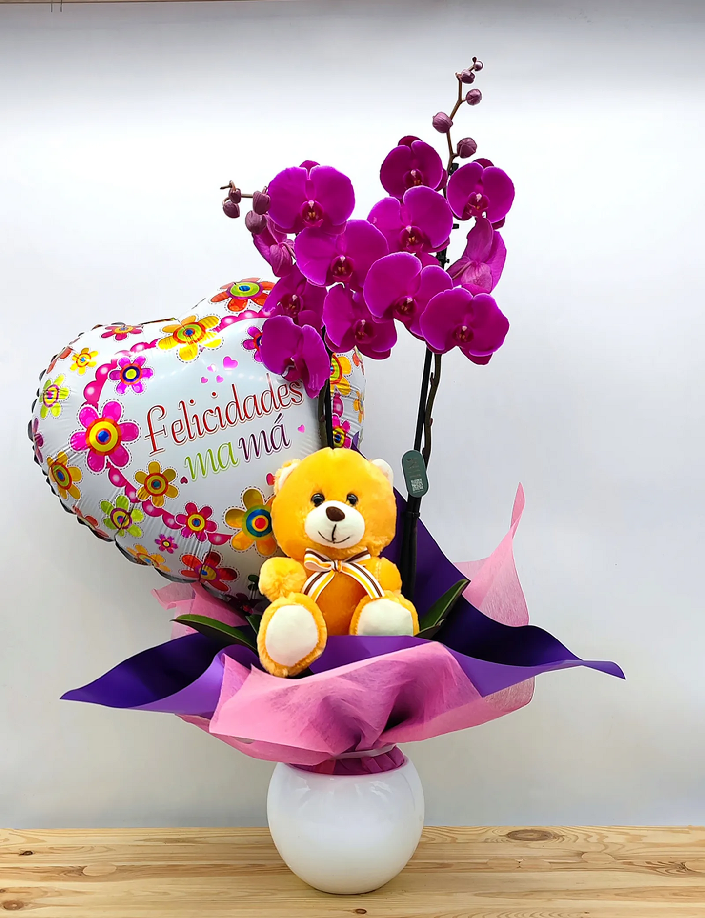 Orquídea con peluche, maceta de cerámica blanca y globo de felicidades mamá
